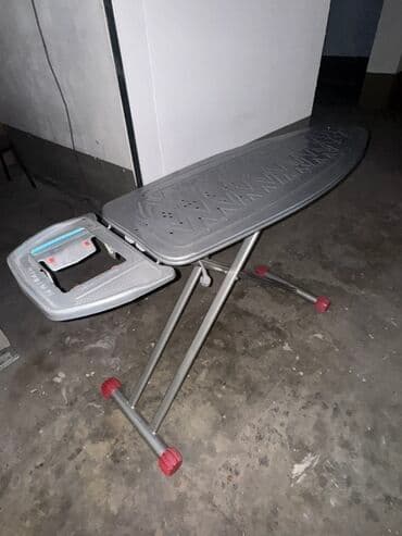 dəmir lövhə: Dəmir ayaqları və qırmızı ucluqları olan boz rəngli ütü masası. Ütü — 1