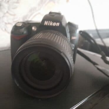 notbuk ucuz: Nikon D90 rəqəmsal güzgülü kamera. Kameranın qara rəngli korpusu var — 2