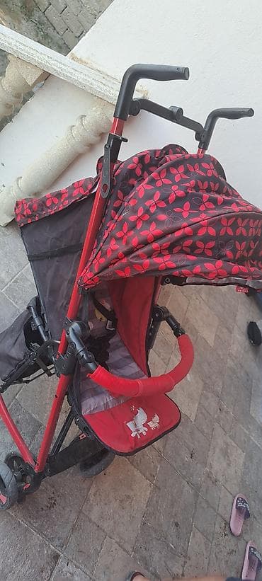 Uşaqlar üçün qırmızı rəngdə, təkərləri olan yüngül uşaq arabası. Bu — 2