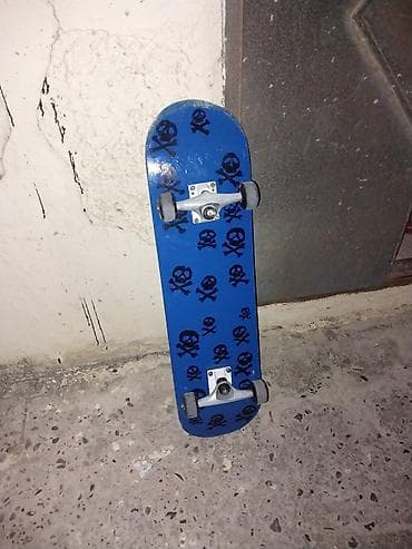 Skateboard – mavi rəngli lövhə, üst səthində qara kəllə-sümüklər