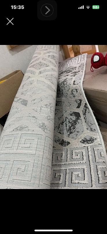 Açıq boz və ağ tonlarda, müasir naxışlı xalça/parça rulonu. Üzərində