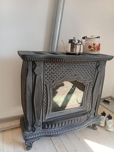 Dekorativ odun sobası – şüşə ön panel və klassik naxışlı korpusla. -