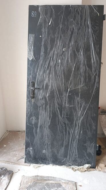 Metal təhlükəsizlik qapısı. Qapının bir tərəfi tünd boz/qara, digər