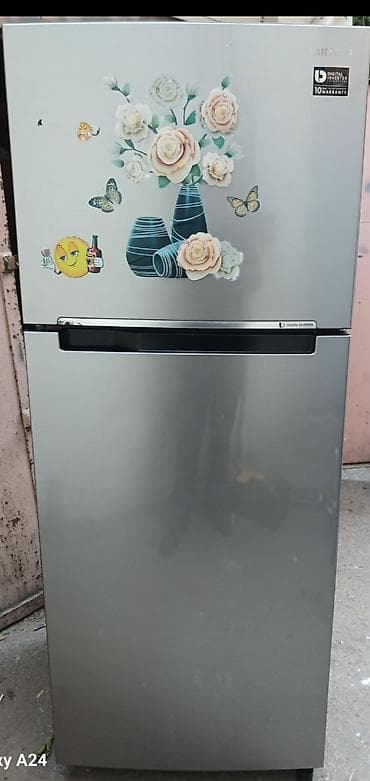 Boz rəngdə, iki bölməli soyuducu. Yuxarı hissə soyuducu, aşağı hissə