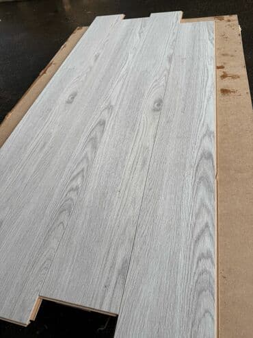 Ağac təqlidli laminat döşəmə örtüyü. Açıq boz rəngdədir və taxta