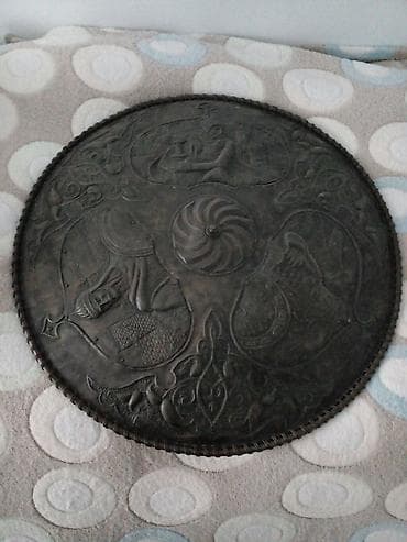 divarda fiqurlar: Dairəvi formada, metal materialdan hazırlanmış bəzək qalxanı. Üzərində — 4