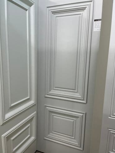 Ağ rəngdə, klassik üslubda qapı. Panelləri olan dizaynı ilə diqqəti