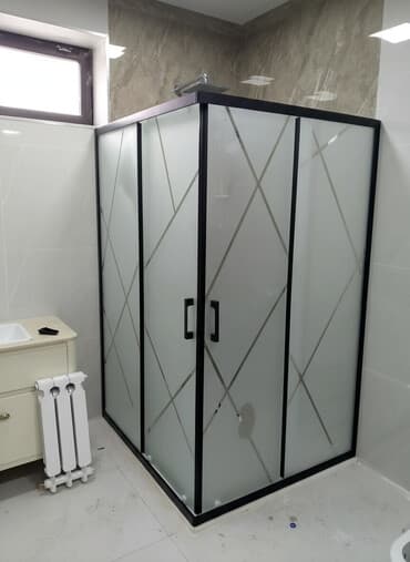 Qara çərçivəli, buzlu şüşəli, müasir dizaynlı duş kabinəsi. Bu kabinə