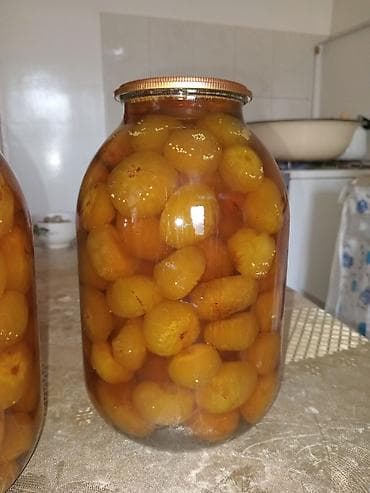 Şəffaf şüşə bankada, qızılı rəngdə tam əncir meyvələri ilə hazırlanmış