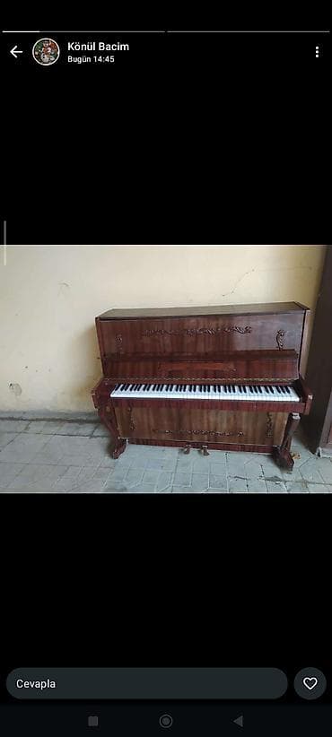 Upright piano – klassik taxta korpus, dekorativ oymalarla. -