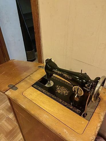 qedimi pullar: Klassik ayaq pedalı ilə işləyən tikiş maşını və taxta dolablı masa — 2