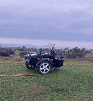 reduktor suretler qutusu: Yan qoşqulu qara motosiklet. Motosikletin ön hissəsində külək şüşəsi — 2