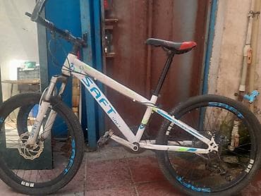SAFT markalı, ağ rəngli dağ velosipedi. Gövdəsinin üzərində mavi və