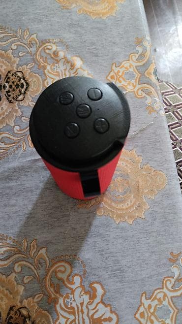 Portativ Bluetooth kolonka – silindrik dizayn, qırmızı torlu örtük və