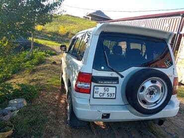 турбо аз трактор: Ağ rəngli, 4 qapılı Mitsubishi Pajero SUV. Avtomobilin arxa hissəsində — 4