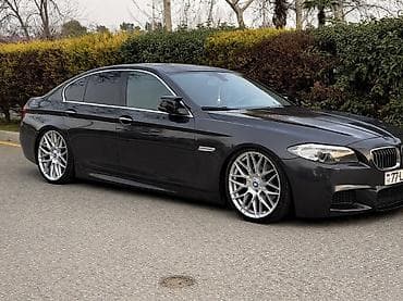 BMW 5 Series sedan – qrafit rəngdə, M paketli xarici görünüş. Aşağı