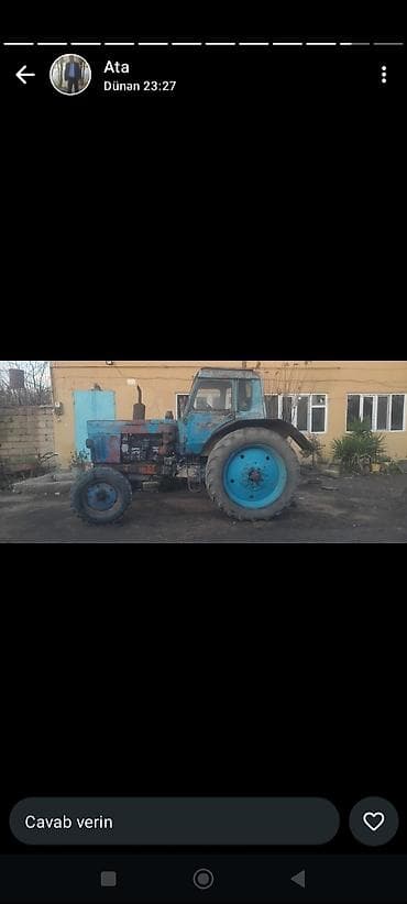 Mavi rəngli sovet istehsalı təkərli traktor. Kabinəli, ön və arxa qoşa