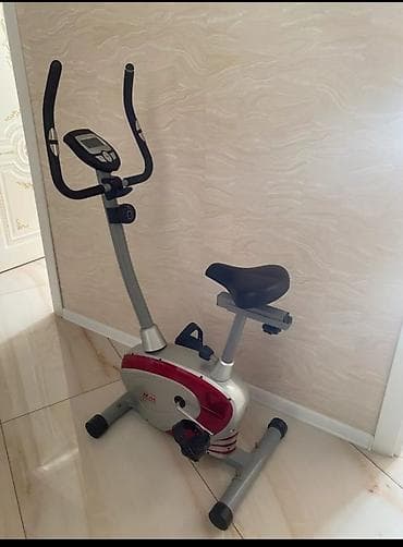 Qırmızı və gümüşü rəngli, elektron displeyli stasionar velosiped. Bu