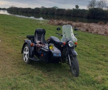 reduktor suretler qutusu: Yan qoşqulu qara motosiklet. Motosikletin ön hissəsində külək şüşəsi — 1