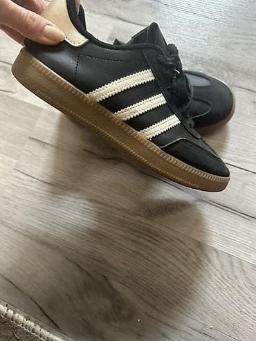 Qara rəngli idman ayaqqabısı, üç ağ zolaqlı klassik dizayn. Üst hissə