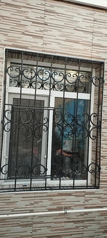 Qara rəngli, dekorativ naxışlı dəmir pəncərə barmaqlıqları. Bu