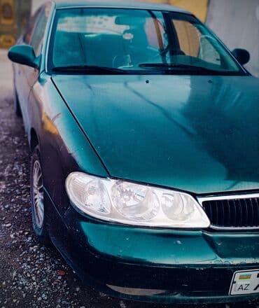 əllə çəkilmiş maşın şəkilləri: Kia Sephia sedan - Kuzov: 4 qapılı sedan, tünd yaşıl rəng - Ön hissə — 2