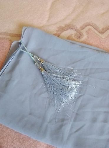 Açıq mavi rəngli şərf/şal – incə, axıcı parça. Uclarında bəzəkli