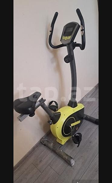 Sarı və qara rəngli, qara oturacağı olan велотренажер. Üzərində idman — 1