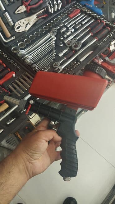 Qırmızı rəngli, tutumlu qum püskürtmə tabancası. Tutma hissəsi rahat