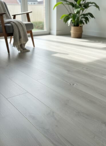 Açıq boz rəngdə, taxta görünüşlü laminat döşəmə panelləri. Panellər