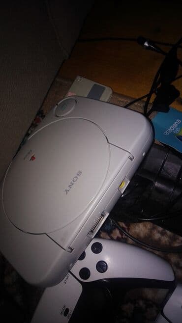 ps2 diskləri: Sony PlayStation One oyun konsolu. Ağ rəngdədir, yığcam dizaynı ilə — 1
