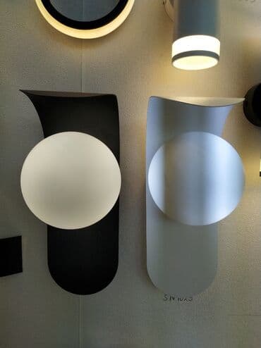 İki müasir divar lampası: biri qara mat fonlu ağ kürə ilə, digəri ağ