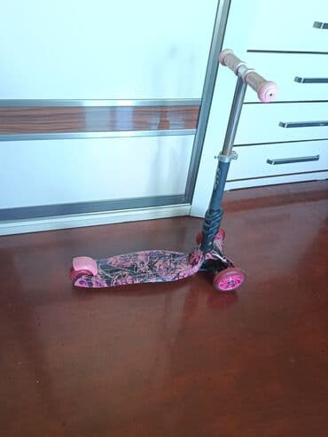 трюковой самокат: Çəhrayı rəngdə və qara naxışlı, üç təkərli uşaq skuteri. Skuterin — 3