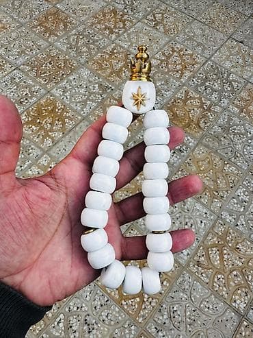 Bu ağ rəngli təsbeh, yuvarlaq muncuqları və qızılı rəngli bəzəkləri