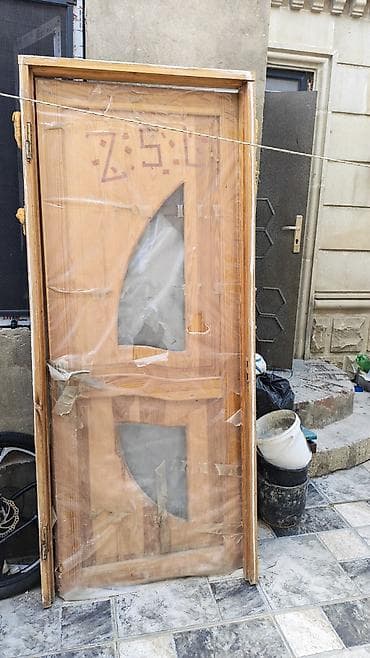 Taxta otaq qapısı, dekorativ şüşəli dizaynda. Qapının üzərində iki