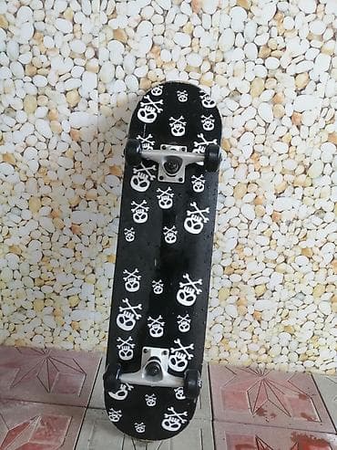 forması: Skateboard – qara rəngli gövdə, üzərində ağ kəllə‑sümük naxışları. - — 2