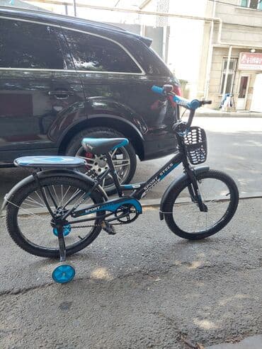 Ön səbəti olan qara və mavi rəngli uşaq velosipedi. Velosipeddə mavi