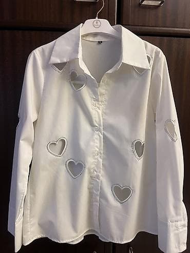 Ağ rəngli qadın köynəyi. Klassik yaxalıqlı və düyməlidir. Parçanın