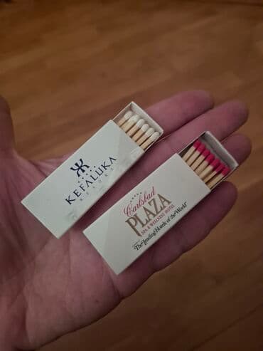 Ağ rəngli iki kibrit qutusu. Birinci kibrit qutusunun üzərində qara