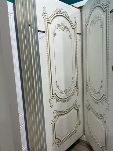 Ağ rəngli, dekorativ elementlərlə bəzədilmiş qapı. Qapının üzərindəki