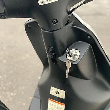 18 disk təkər: Gümüşü rəngdə, qara detallarla bəzədilmiş Suzuki skuter. Bu model — 6