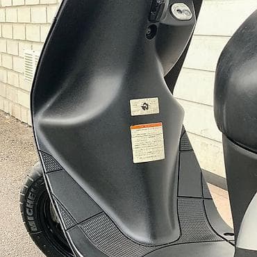 18 disk təkər: Gümüşü rəngdə, qara detallarla bəzədilmiş Suzuki skuter. Bu model — 9