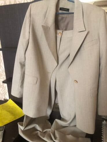 Bej rəngdə iki parçalı qadın kostyumu. Kostyumun pencəyi klassik