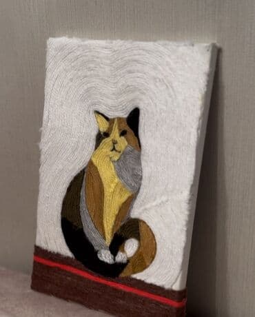 Bu, rəngli ipliklərdən hazırlanmış, pişik təsviri olan əl işi sənət