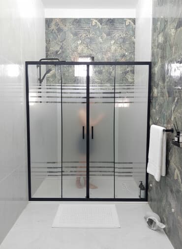 Qara çərçivəli, buzlu şüşəli duş kabinəsi. Müasir dizaynı və zolaqlı