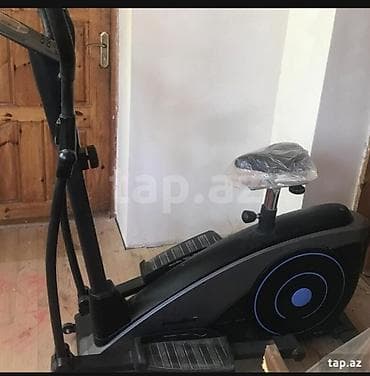 InQara rəngdə, oturacağı olan elliptik trenajor. Evdə idmanla məşğul