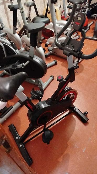 velotrenajorlar: Qara rəngdə olan, qırmızı detalları olan stasionar velosiped. Üzərində — 1