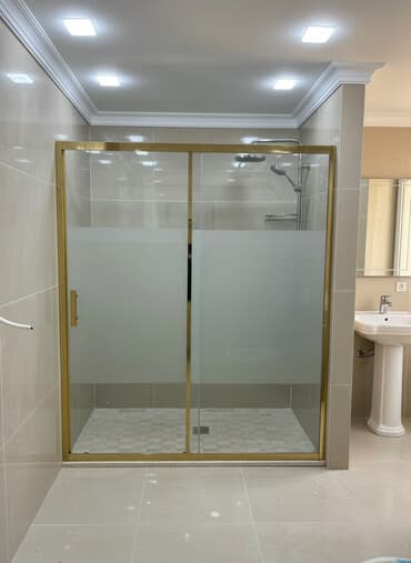 Qızılı rəngli çərçivəyə malik sürüşən şüşəli duş kabinəsi. Mat şüşəsi