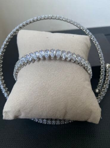 Zərif gümüşü rəngli qolbaq dəsti, hər biri parıldayan şəffaf daşlarla