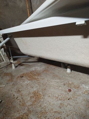 Ağ rəngli, düzbucaqlı formalı vanna. Metal ayaqları və bərkitmə